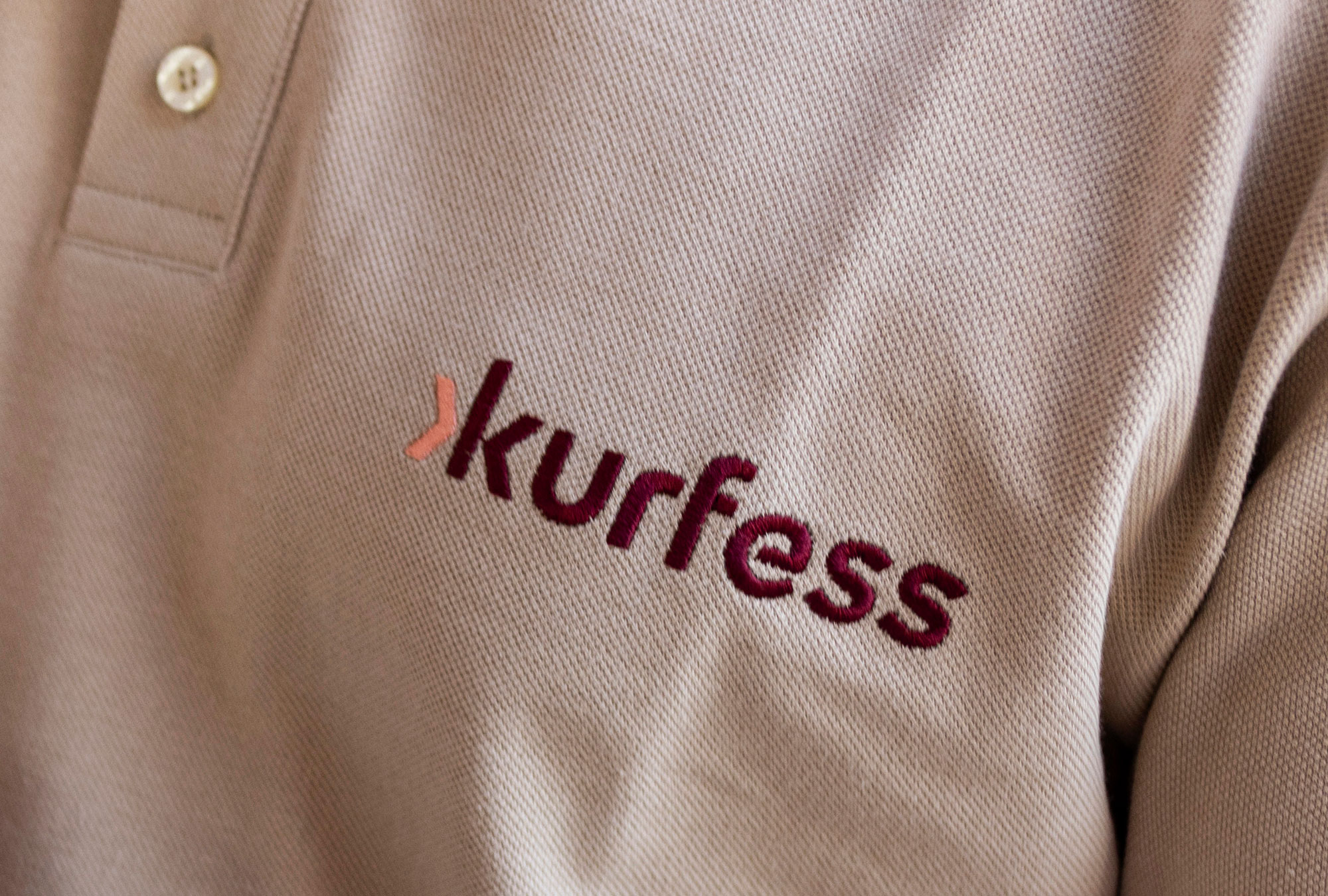 Detailaufnahme eines hellen Hemds mit gesticktem Kurfess Logo